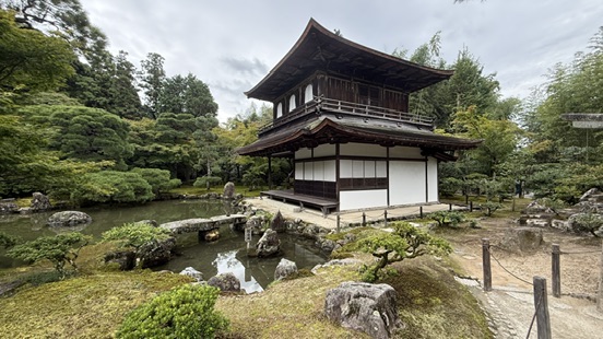 銀閣寺觀音殿深色木造二層建築,白牆黑瓦,周圍是水池與松樹