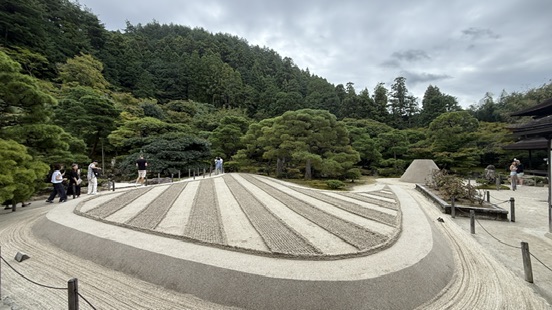 銀閣寺觀音殿深色木造二層建築,白牆黑瓦,周圍是水池與松樹