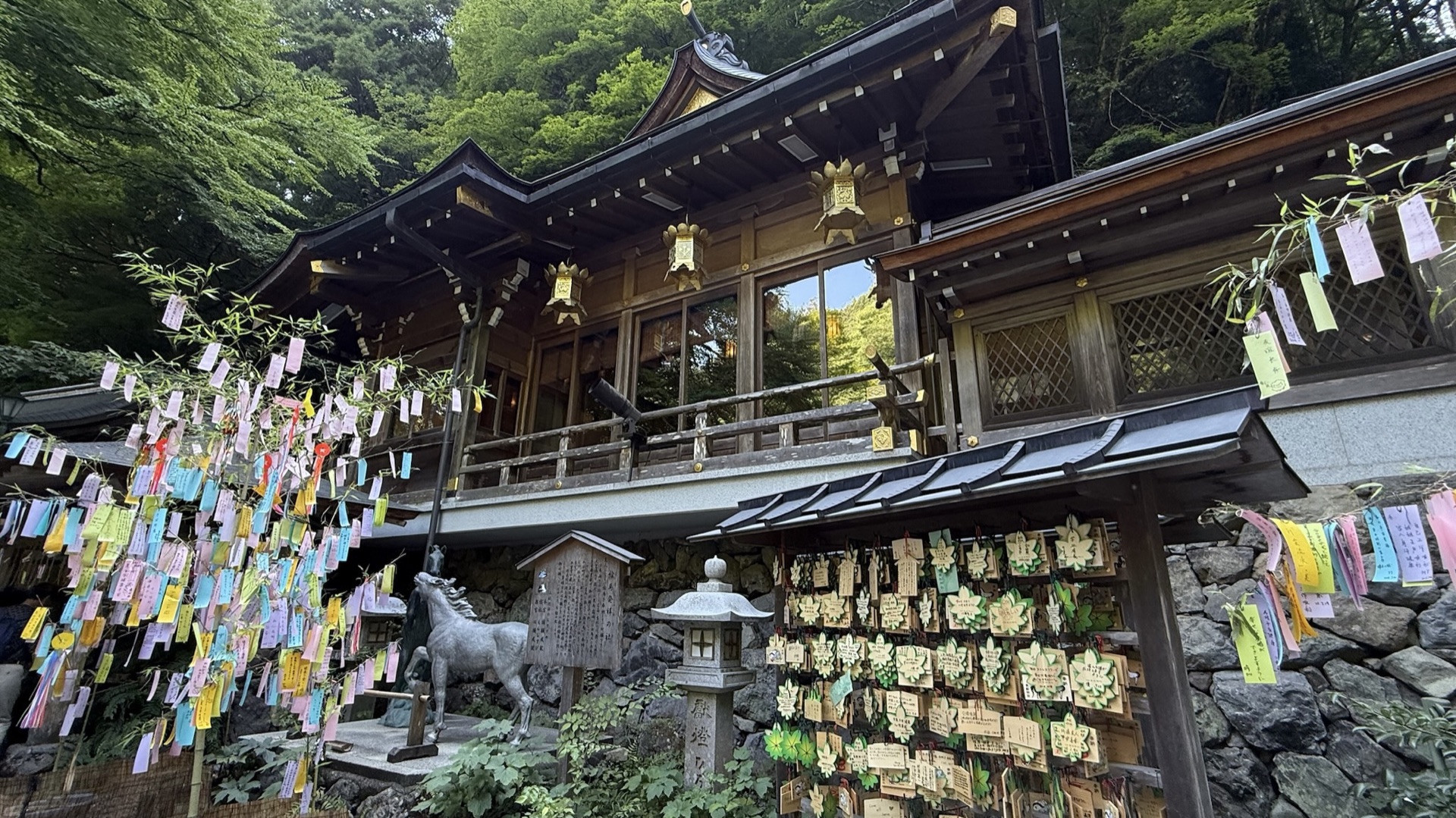 貴船神社本殿,木造社殿前掛滿繪馬與短冊,周圍是茂密山林