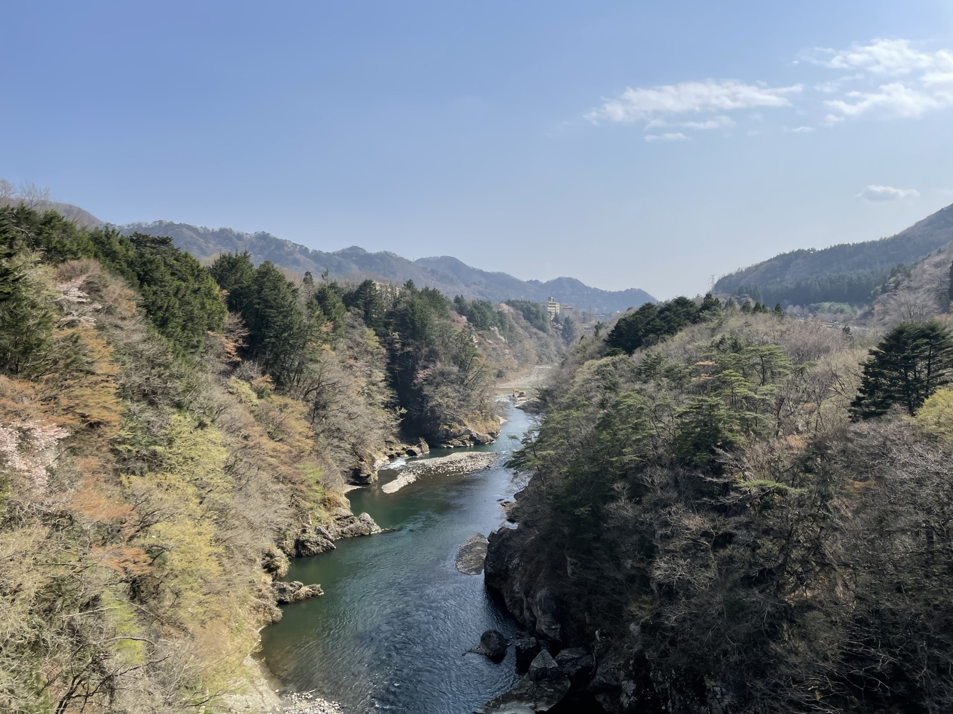 鬼怒川溫泉站前廣場,前景是手持棒槌的鬼怒太青銅雕像,背景為群山與溫泉旅館街