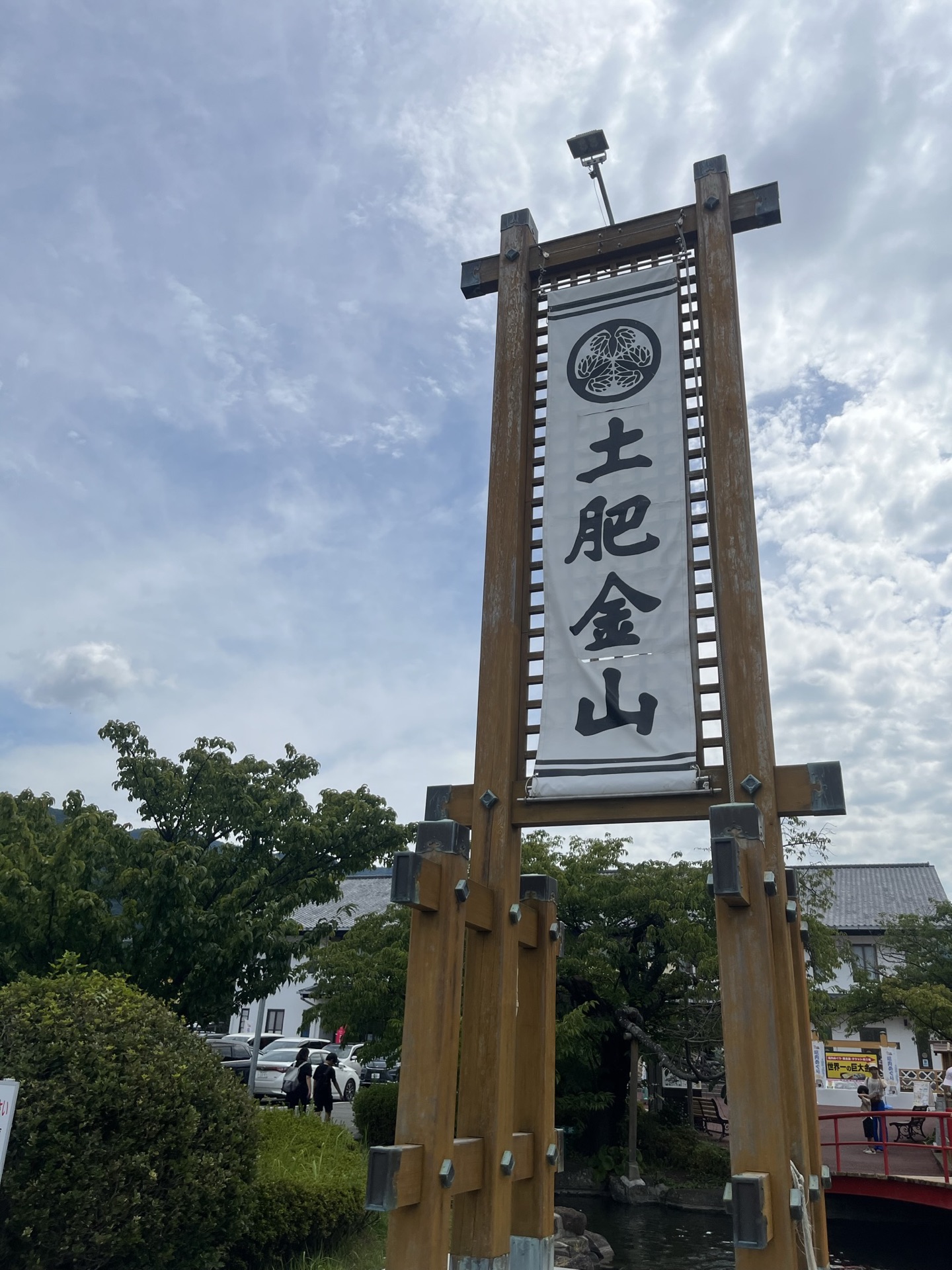 土肥金山入口木製招牌,白色布幔上寫「土肥金山」三字,背景為晴天