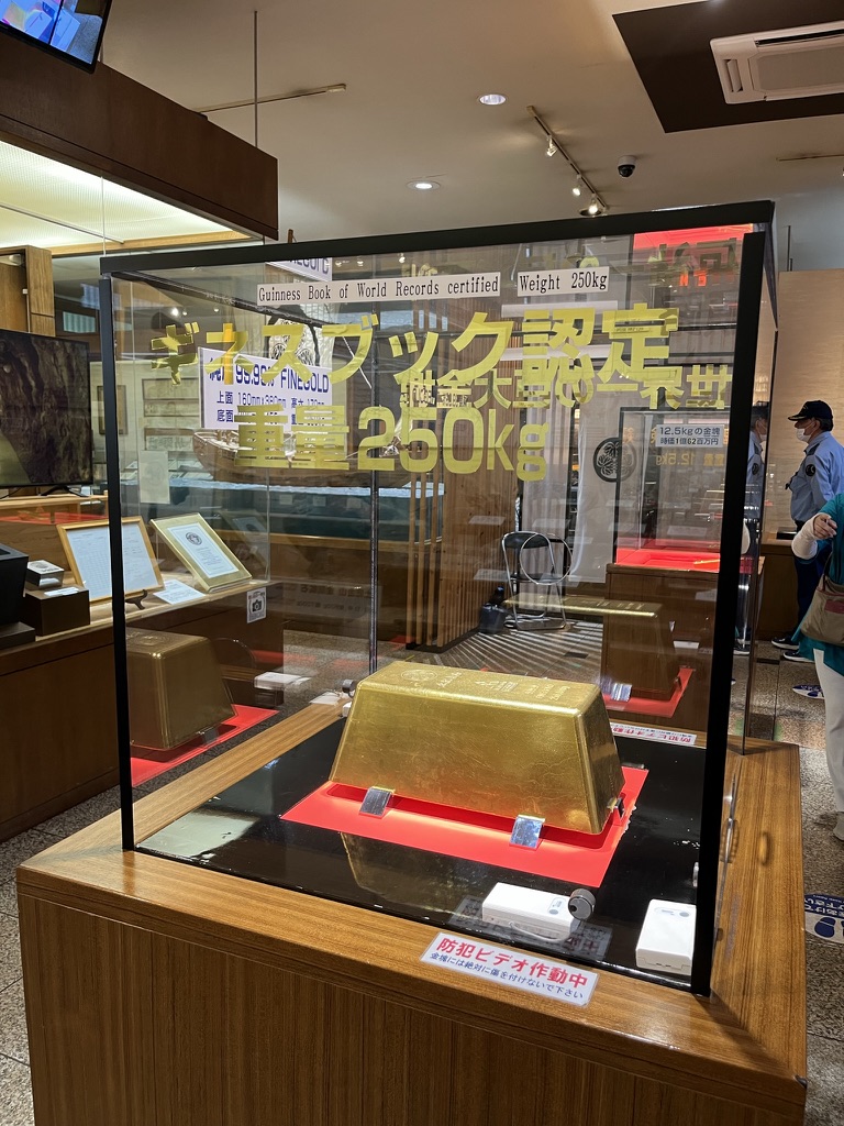 土肥金山入口木製招牌,白色布幔上寫「土肥金山」三字,背景為晴天